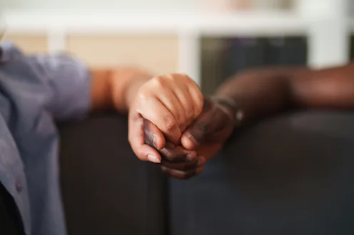 Close-up of a young interracial couple holding hands while spending time together at home. A quiet m...