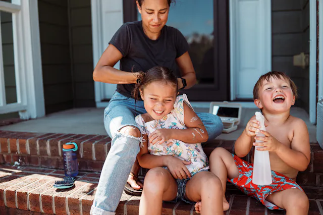 A five-year-old Eurasian girl sits on the front steps of her suburban home with her playful little b...