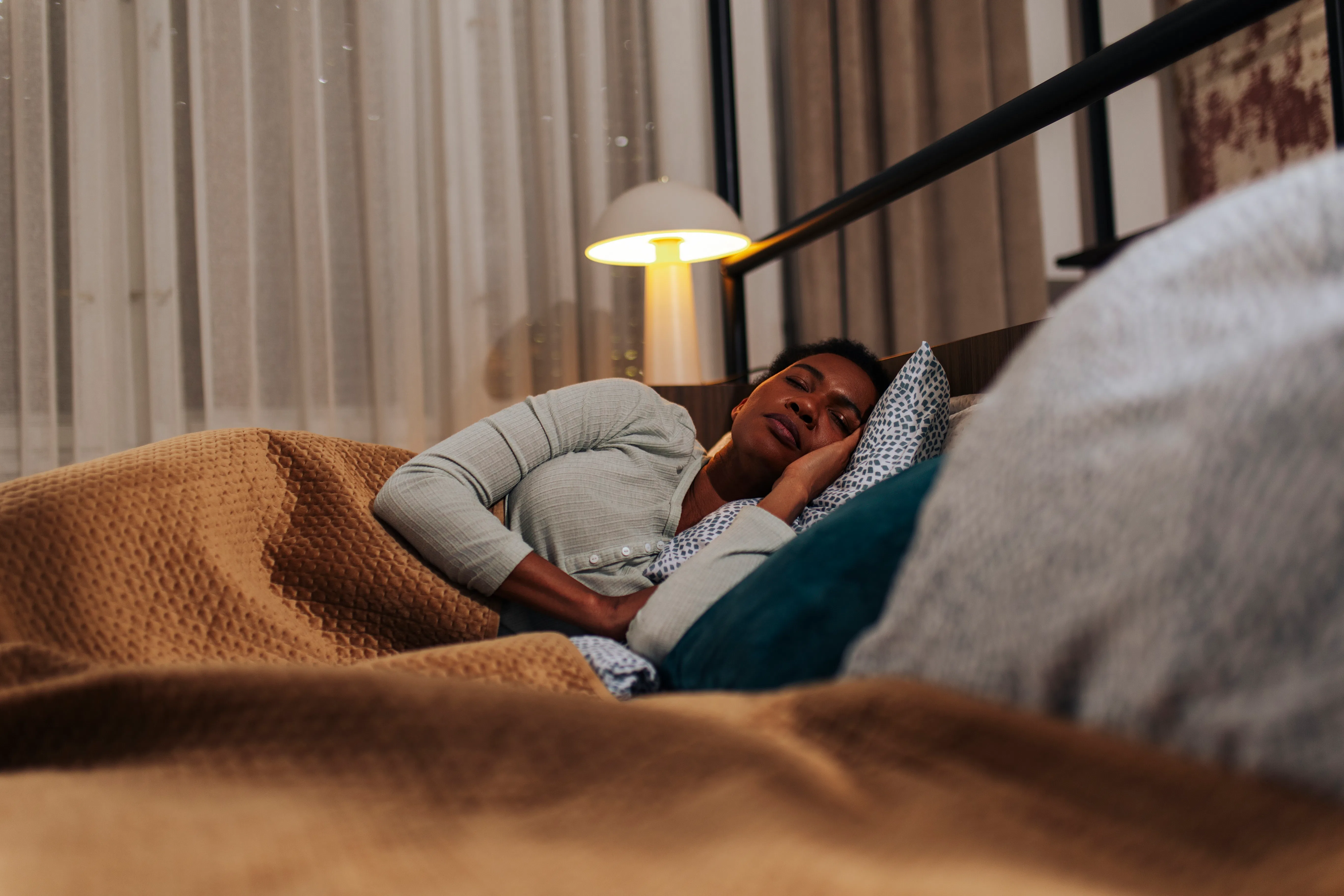 Mid adult African American woman enjoying a restful night's sleep in a cozy bed. Healthy lifestyle, ...