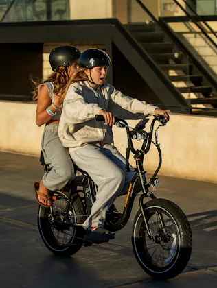 People ride an e-bike on the Strand in Hermosa Beach.