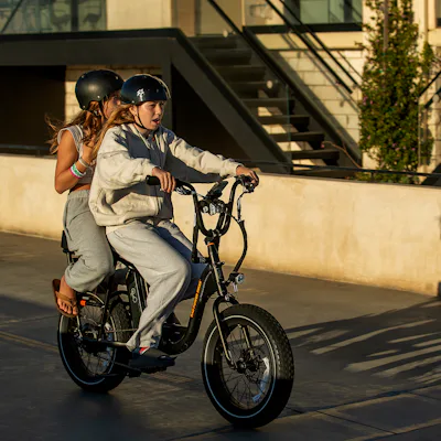 People ride an e-bike on the Strand in Hermosa Beach.