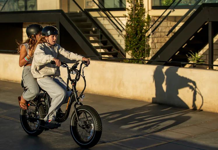 People ride an e-bike on the Strand in Hermosa Beach.