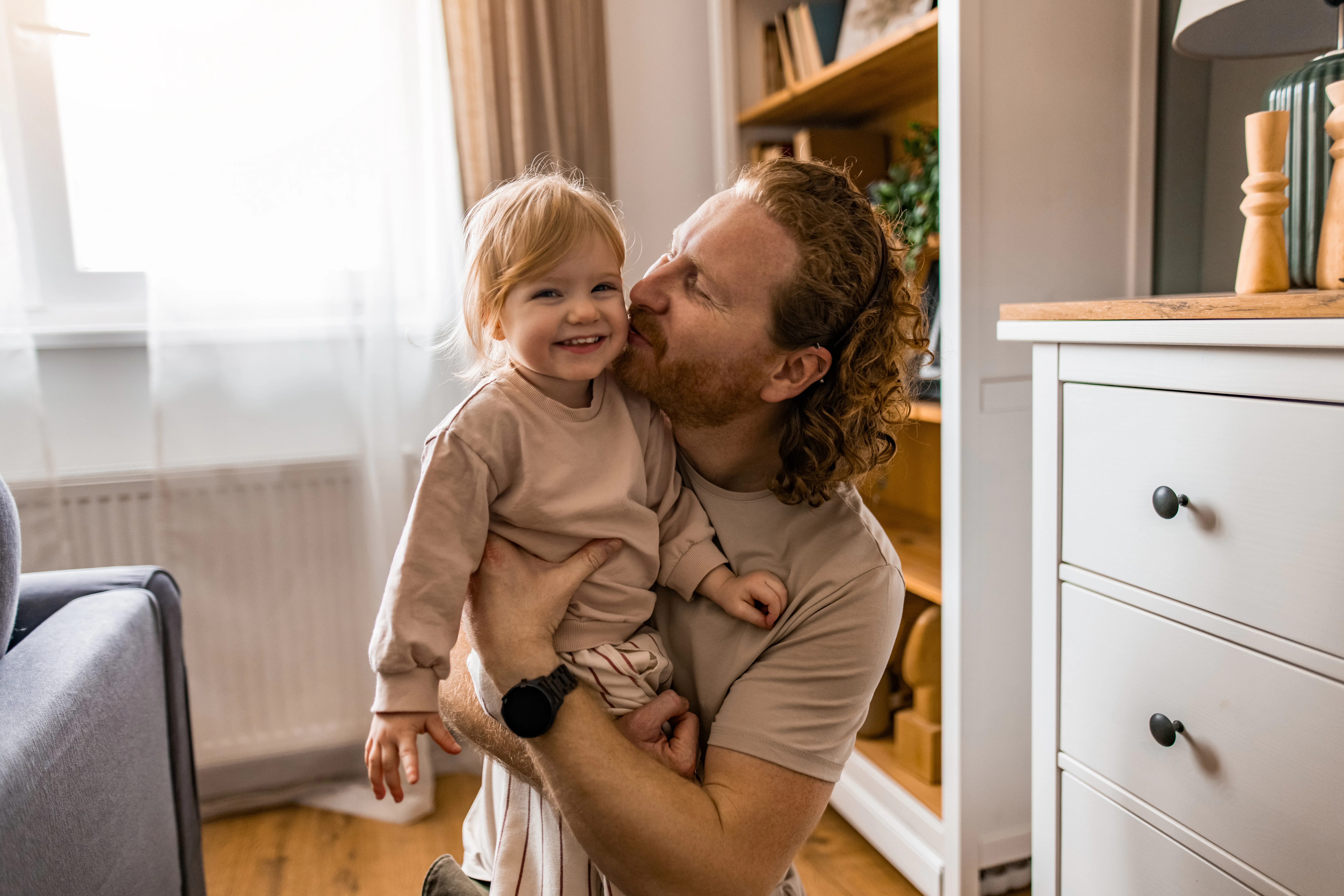 Close-up of father and his little daughter embracing in the living room.