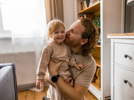 Close-up of father and his little daughter embracing in the living room.
