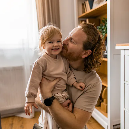 Close-up of father and his little daughter embracing in the living room.