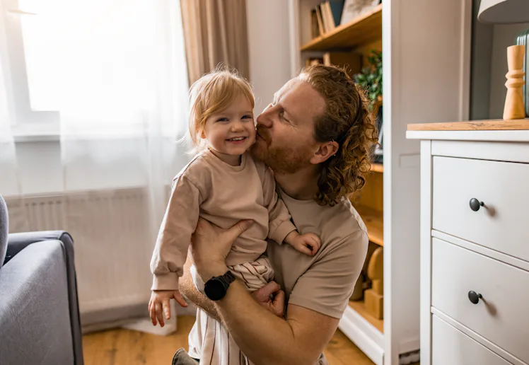 Close-up of father and his little daughter embracing in the living room.