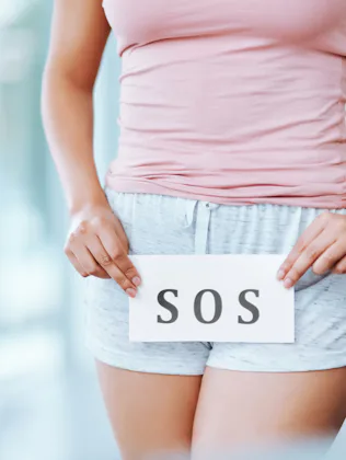 Cropped shot of an unrecognizable woman holding an SOS sign in front of her private parts
