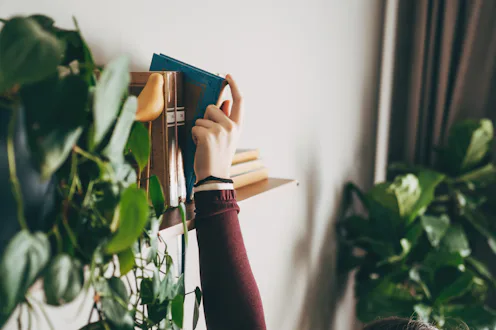 A young woman chooses a book to read at home, relaxation and a slow life. A gadget detox.
