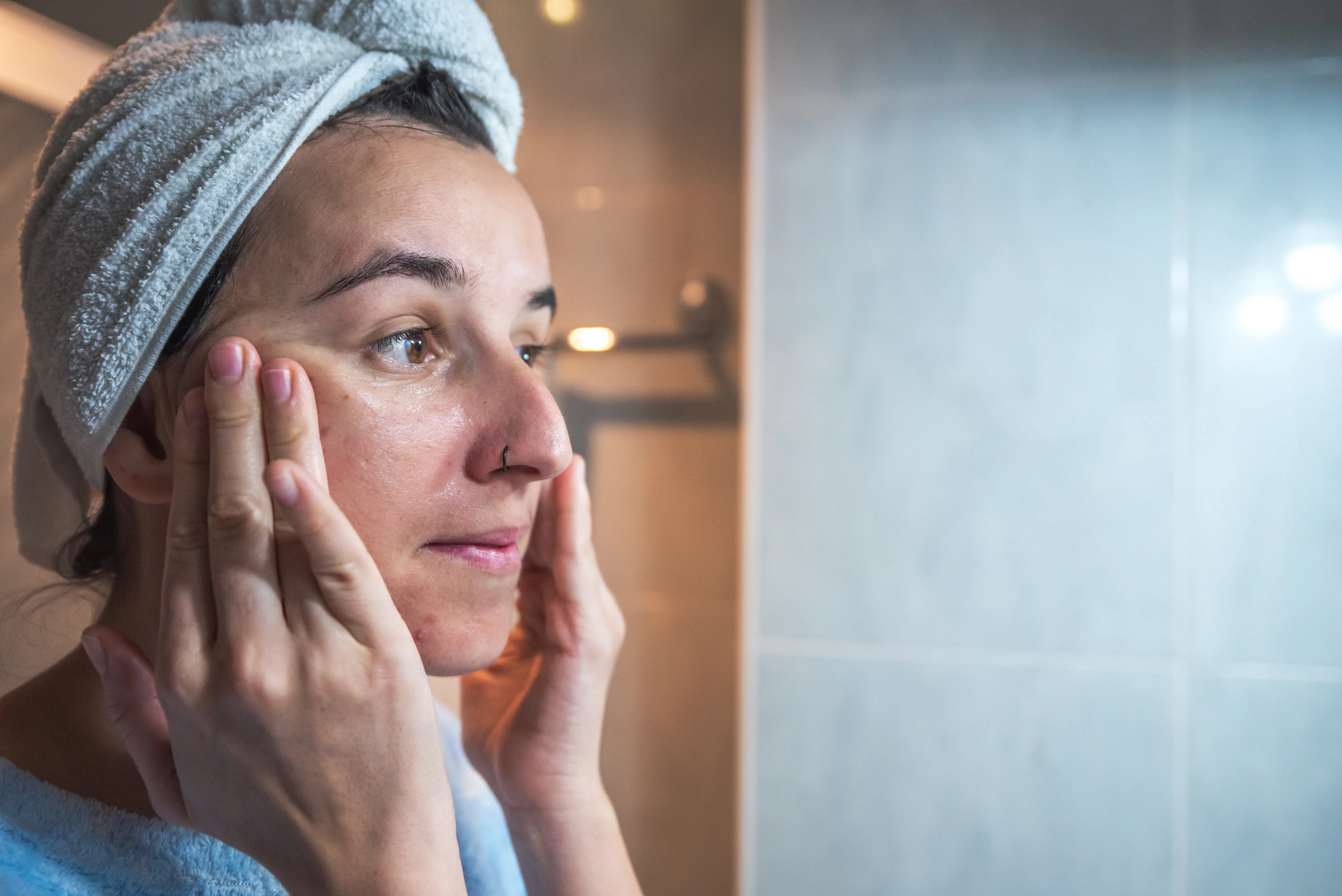 Young woman massaging her face with her hands after applying cream