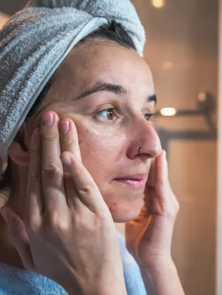 Young woman massaging her face with her hands after applying cream