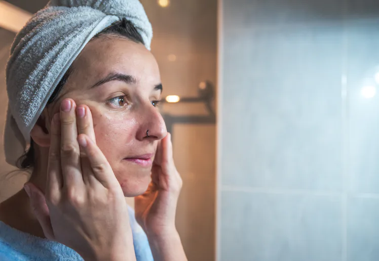 Young woman massaging her face with her hands after applying cream