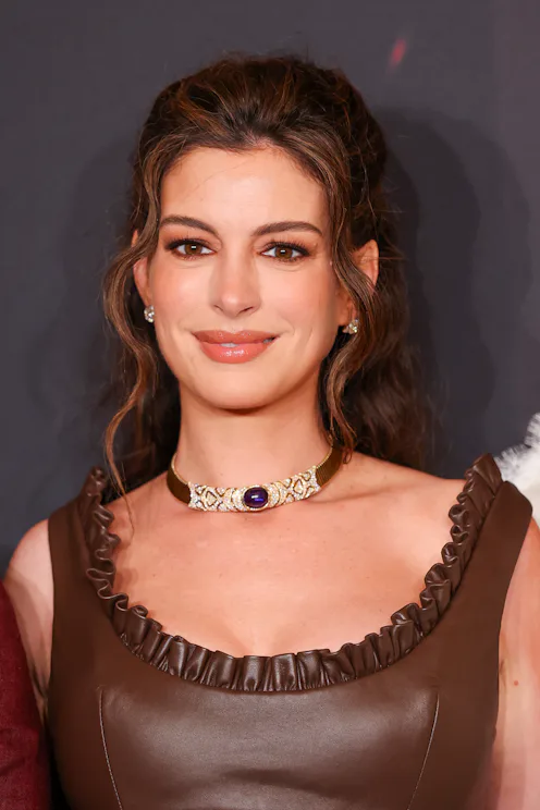 Anne Hathaway at a premiere for The Odyssey with neutral makeup and a brown gown