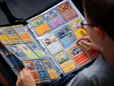 BERLIN, GERMANY - AUGUST 18: A symbolic photo of Pokemon. A boy looks at Pokemon cards in a scrapboo...