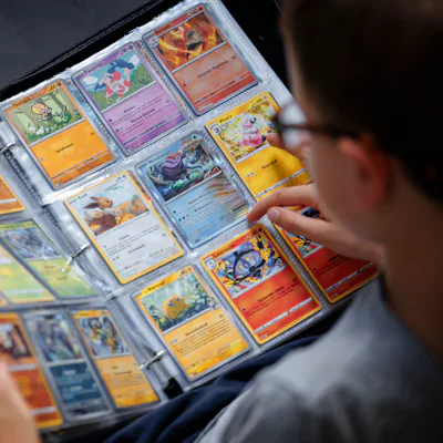 BERLIN, GERMANY - AUGUST 18: A symbolic photo of Pokemon. A boy looks at Pokemon cards in a scrapbook on August 18, 2025 in Berlin, Germany. (Photo Illustration by Thomas Trutschel/Photothek via Getty Images)