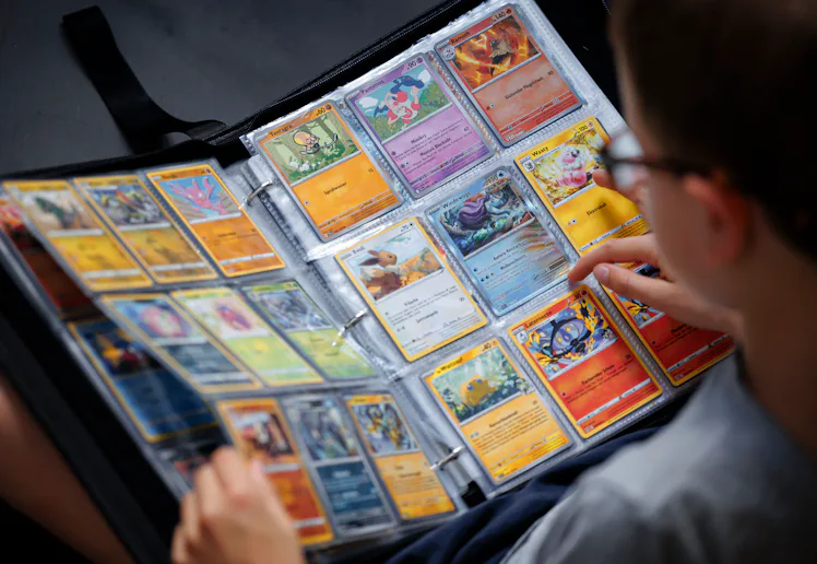BERLIN, GERMANY - AUGUST 18: A symbolic photo of Pokemon. A boy looks at Pokemon cards in a scrapboo...