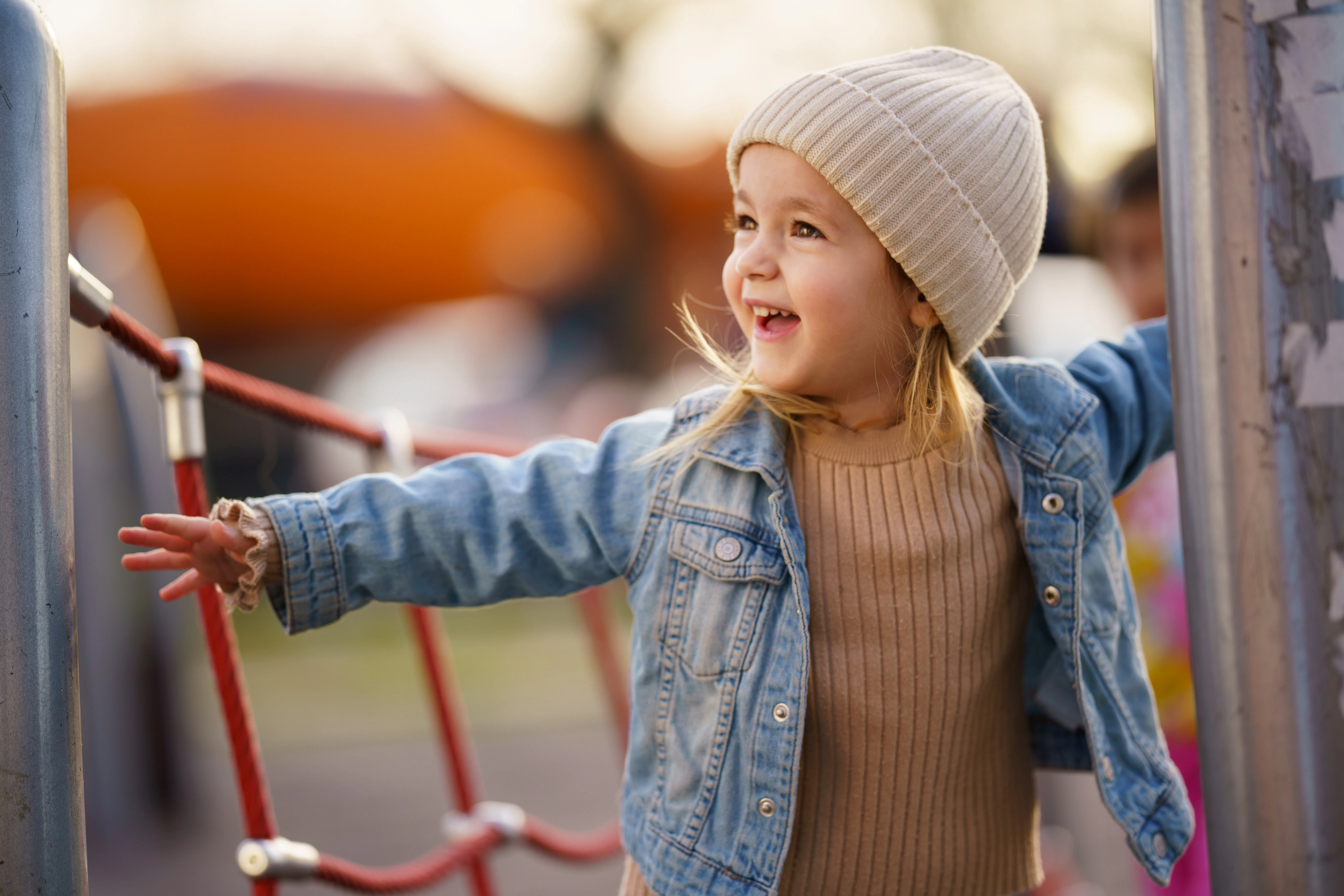 Smiling little girl enjoying playing on climbing frame at playground.