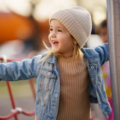 Smiling little girl enjoying playing on climbing frame at playground.