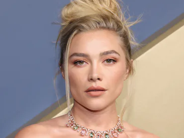 Florence Pugh at the 2026 Emmy Awards with a tousled updo and peachy makeup