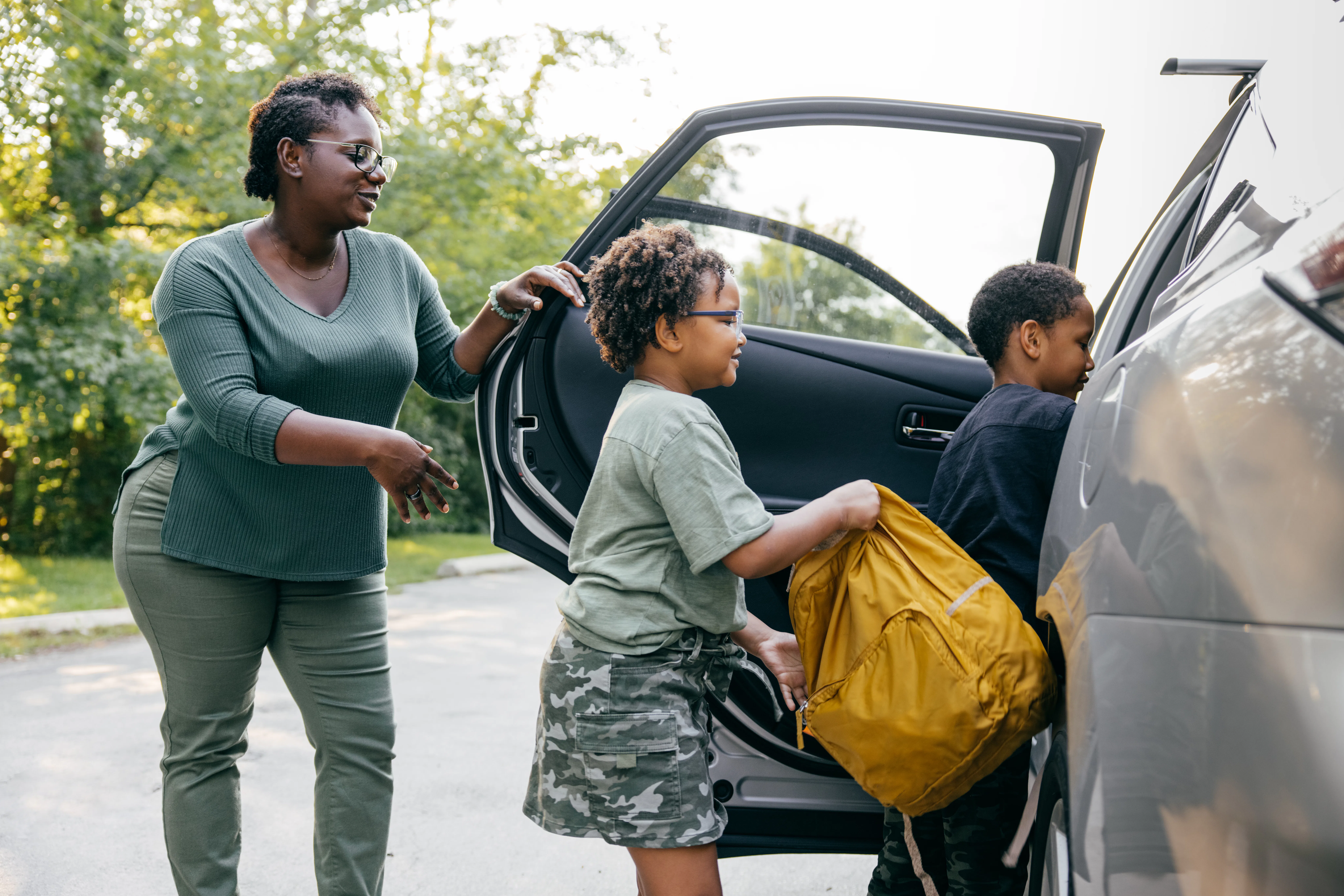Shot of black family entering a car on their first day back to school.
