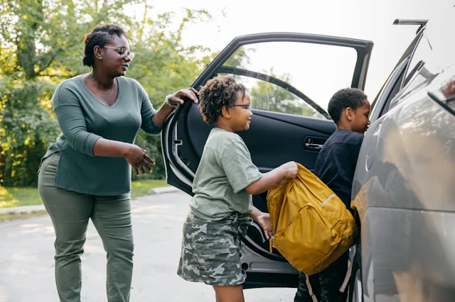 Shot of black family entering a car on their first day back to school.