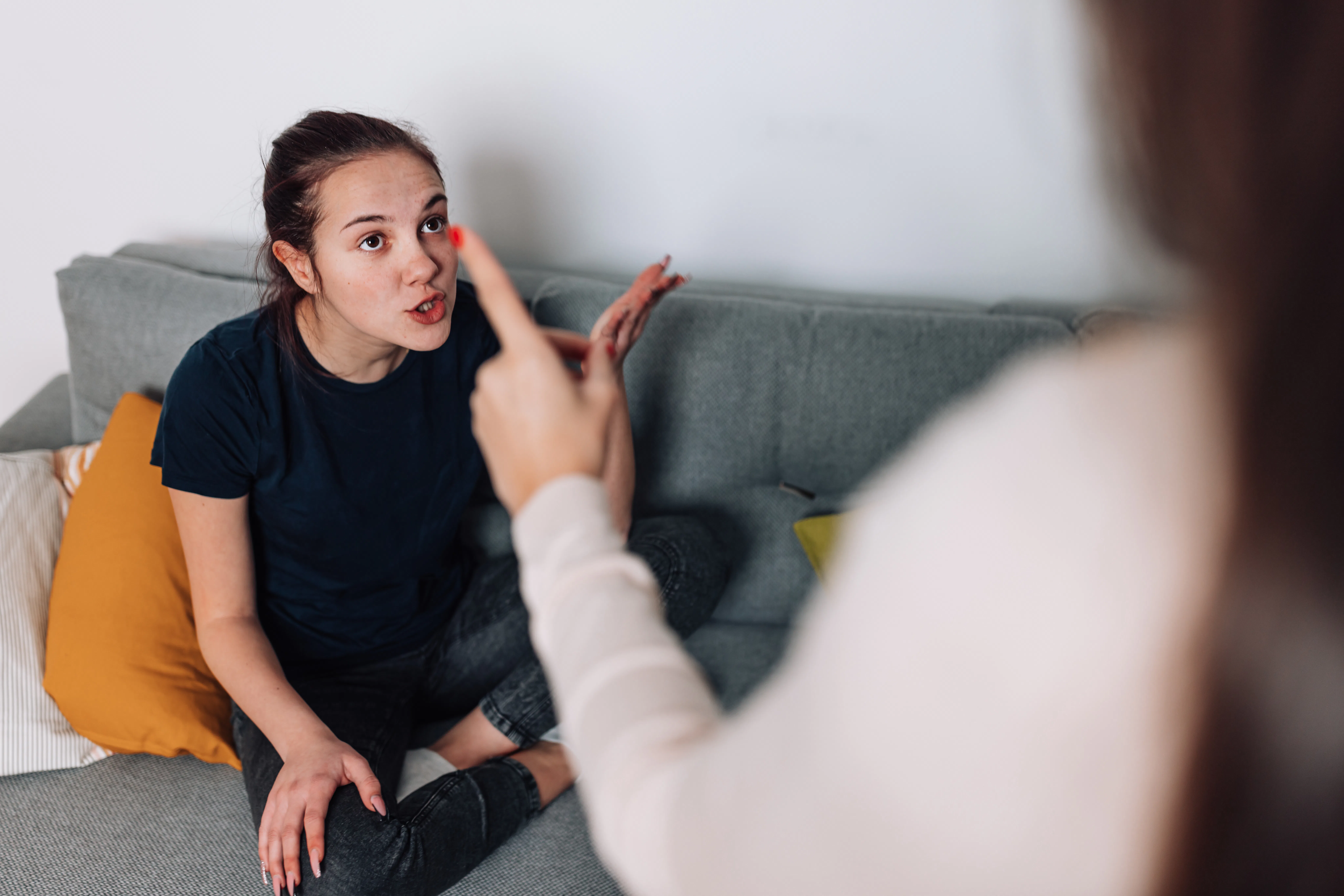 A mother and teenage daughter sit in the living room, discussing their differences and trying to wor...