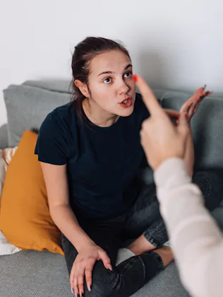 A mother and teenage daughter sit in the living room, discussing their differences and trying to wor...