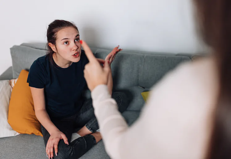 A mother and teenage daughter sit in the living room, discussing their differences and trying to wor...