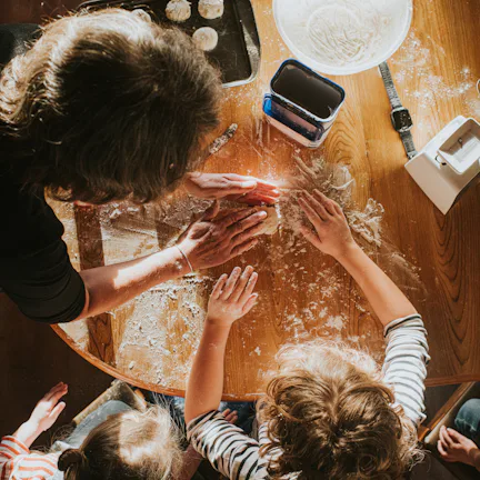 Top down image of three children baking scones with thier grandmother. The scene is messy and busy.