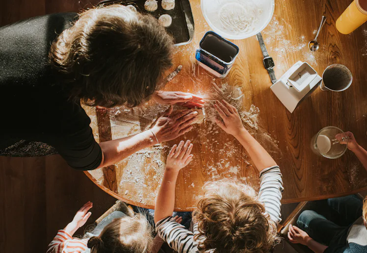 Top down image of three children baking scones with thier grandmother. The scene is messy and busy.