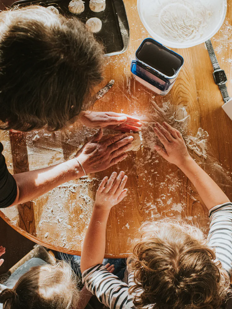 Top down image of three children baking scones with thier grandmother. The scene is messy and busy.