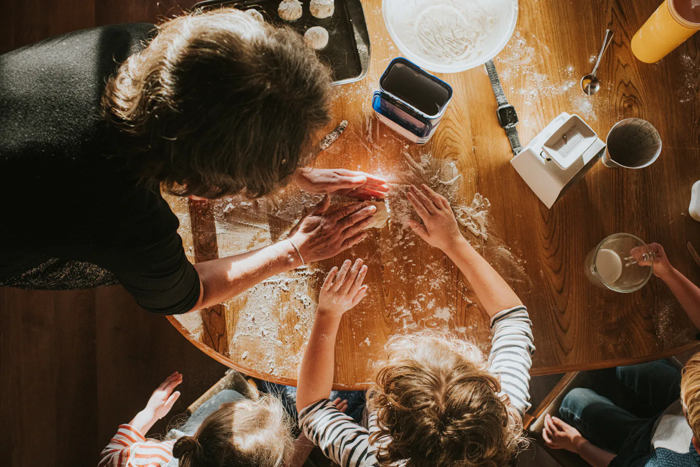 Top down image of three children baking scones with thier grandmother. The scene is messy and busy.