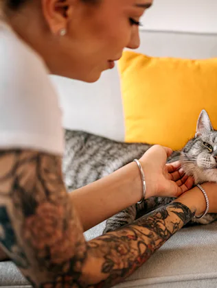 Young woman petting and showing love to her cat at home