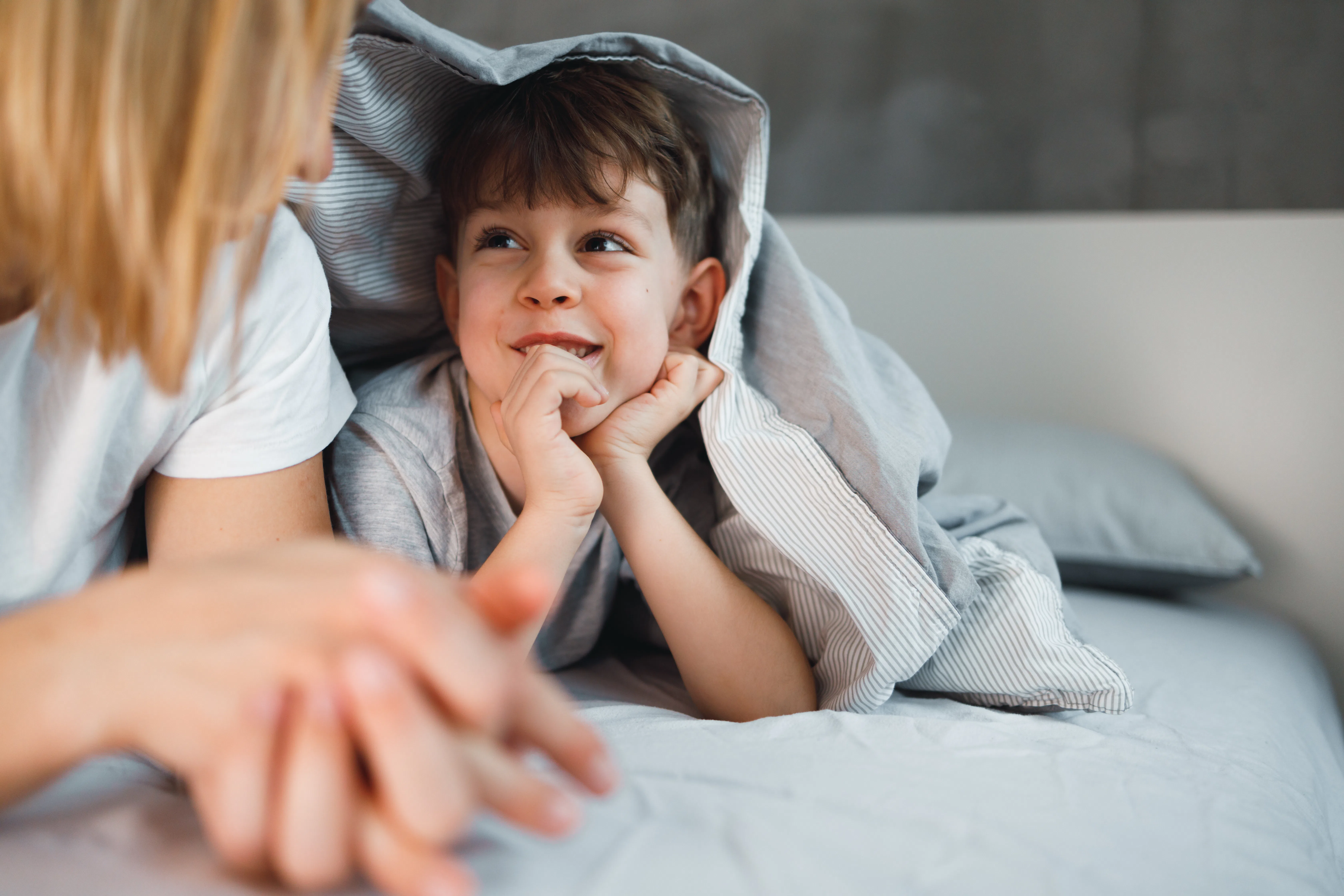 Mother is telling a story to her 7 years old son in the bed.