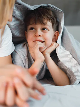 Mother is telling a story to her 7 years old son in the bed.