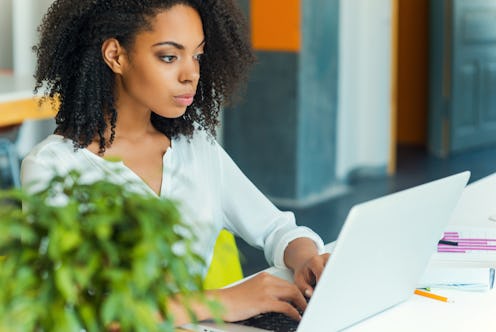 A curly-haired woman in a white shirt, building her personal brand on LinkedIn
