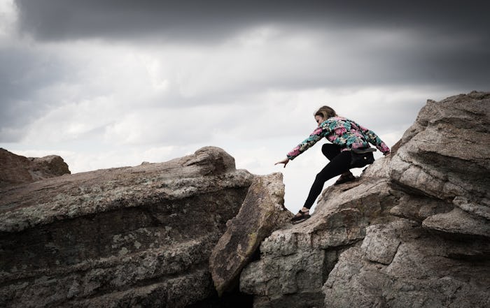 AJ Yorio going over difficult rocky terrain while dark clouds appear in the sky.