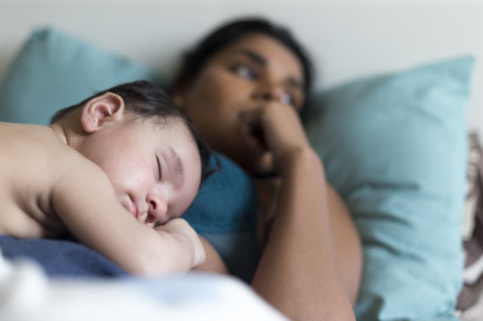 A mom lying on her bed and doesn't want to be touched and her child sleeping on her stomach