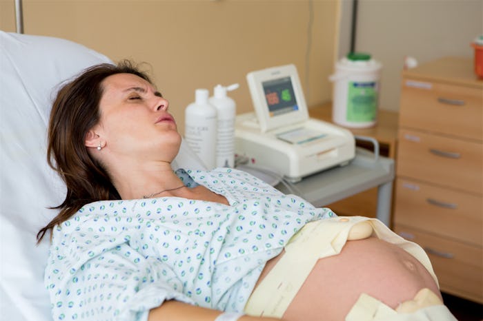 A brunette pregnant woman lying in a hospital bed during effacement 