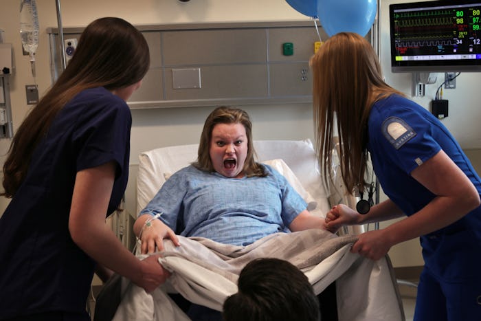 A woman surrounded by two nurses during childbirth with a lack of privacy