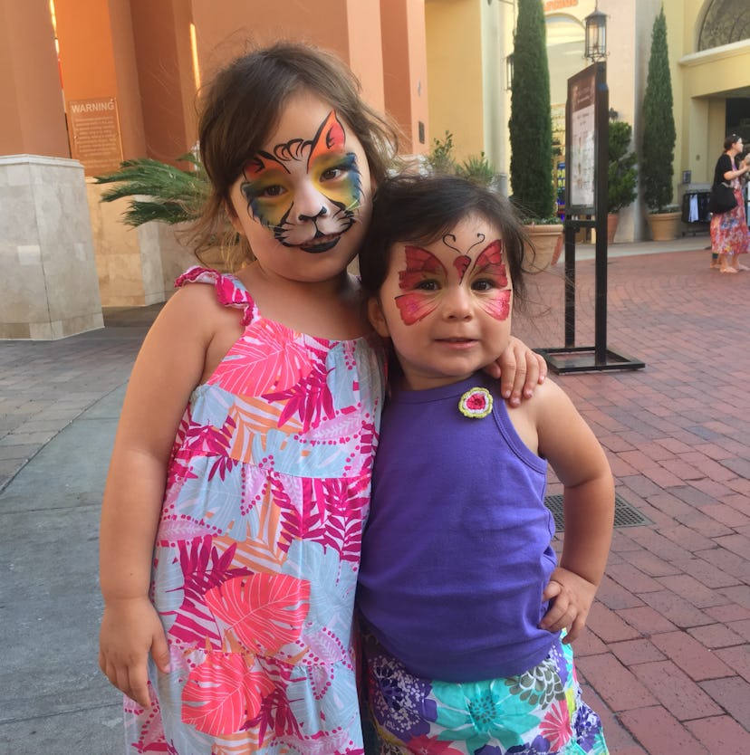 Two girls with face paint on hugging each other while posing for a photo