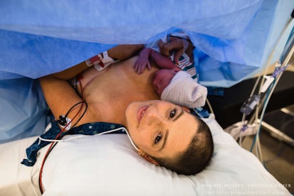 Woman posing for a photo while holding her baby in hospital right after giving birth