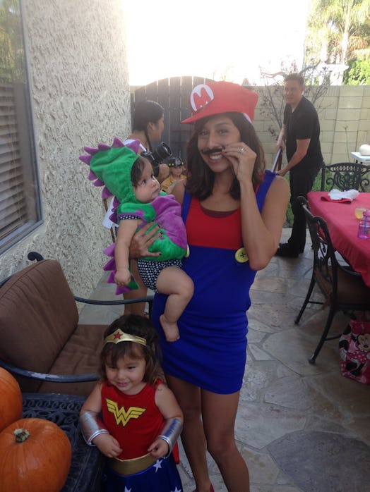 Ambrosia dressed up as a Super Marion, holding her daughter