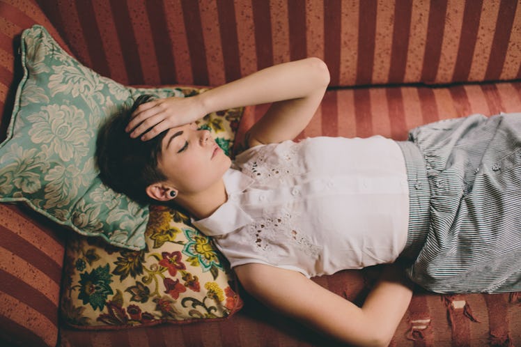 a girl laying on a couch while having throbbing headache