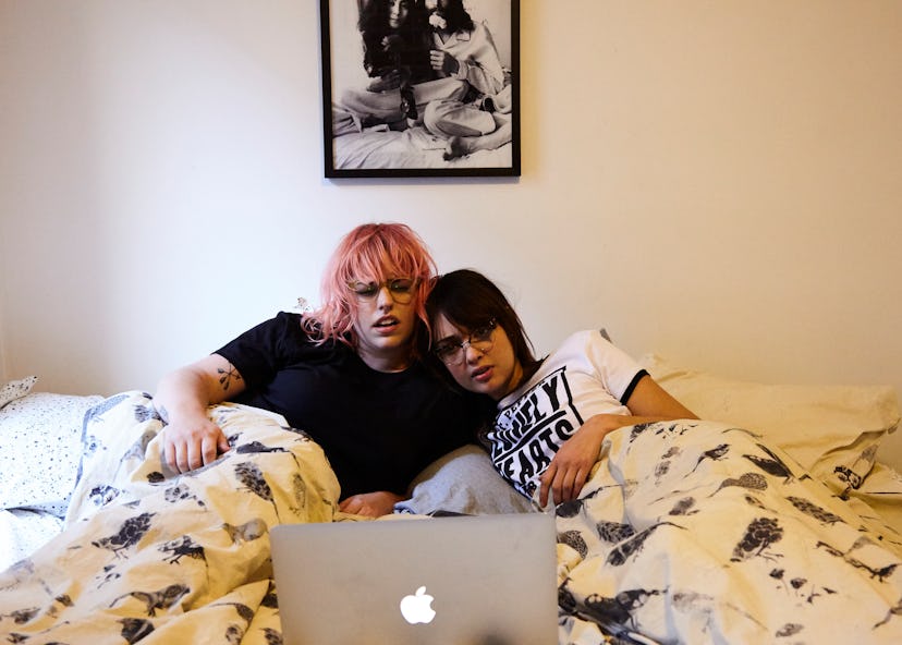 Girlfriends lying on the bed and watching a movie on the laptop