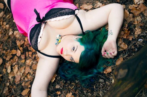 Sarah Martindale lying in a pink-and-black slip dress on dried leaves