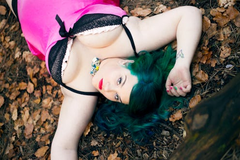 Sarah Martindale lying in a pink-and-black slip dress on dried leaves