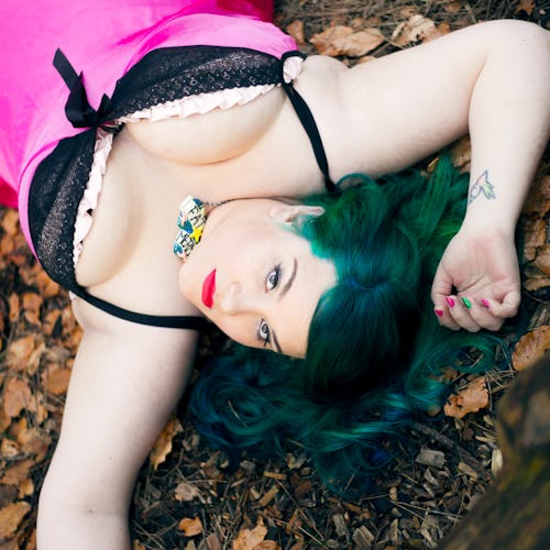 Sarah Martindale lying in a pink-and-black slip dress on dried leaves