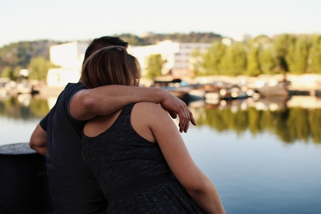A picture of a satisfied couple hugging each other and looking toward the lake