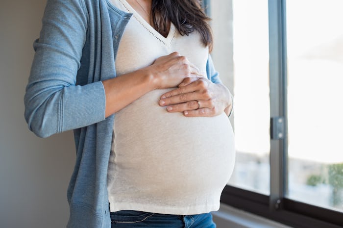 A closeup of a woman with gestational diabetes rubbing her pregnant belly