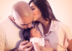 Couple holding a baby together and kissing as a representation of a parent being left alone with a n...